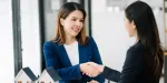 Corretora imobiliária fechando uma transferência de imóvel com cliente.